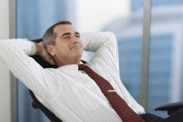 business man in tie leaning back in office chair and looking pleased and relaxed