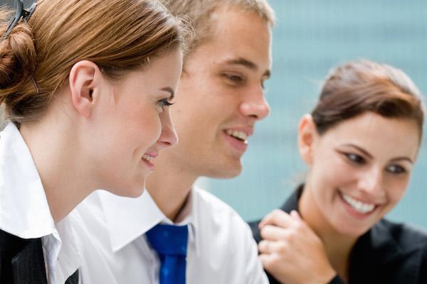 three young professional smiling and pleased at what they are looking at