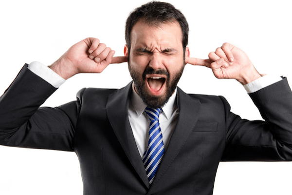 man in suit with his fingers in his ears and yelling with his eyes closed