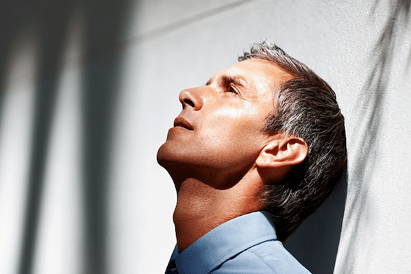 business man with head against the wall, looking distressed and depressed