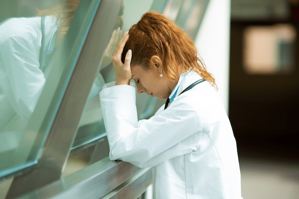 Health worker holding head and looking discouraged