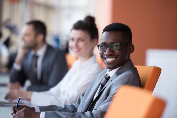 business people at a conference table with one man in focus smiling broadly