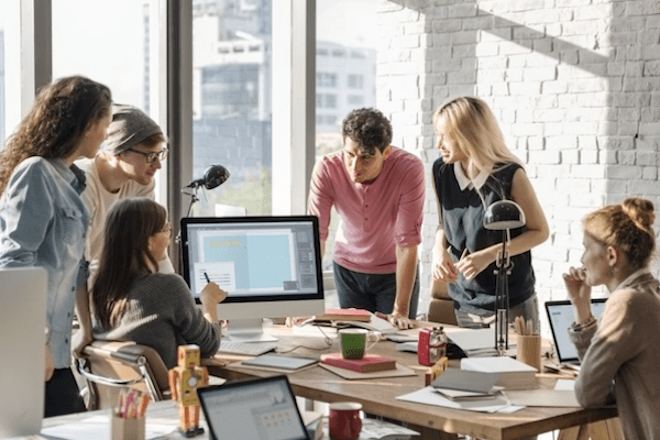 six coworkers are focused on woman presenting something on screen