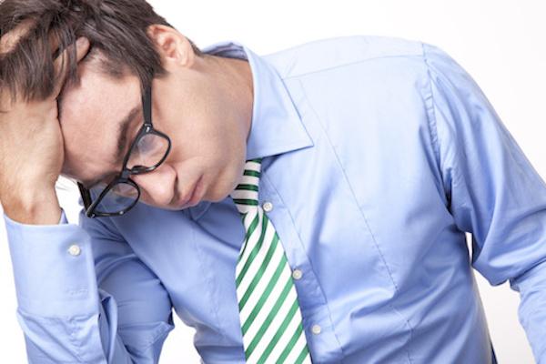 man with hand on head and looking down as if stressed out