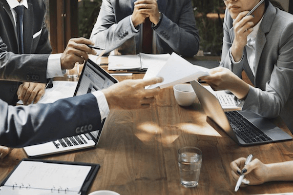 professionals working around a conference table with laptops phones and more