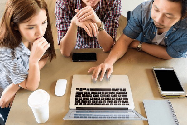 three people looking at a laptop with one touching the keyboard