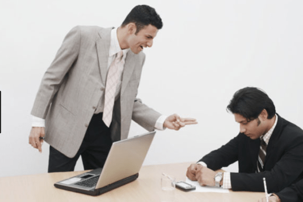 Two men in suits with one yelling and pointing at the other one who has his head down as if ashamed