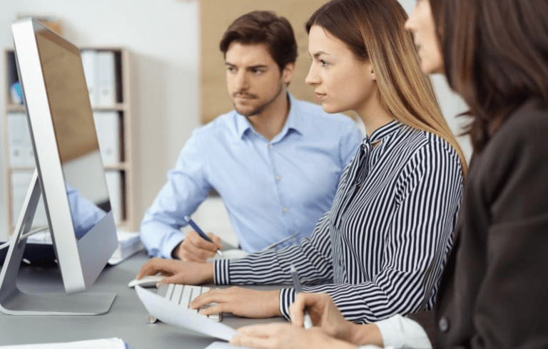 three coworkers looking intently at computer screen