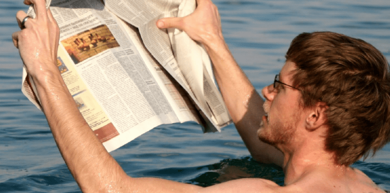 man reading a newspaper while in water