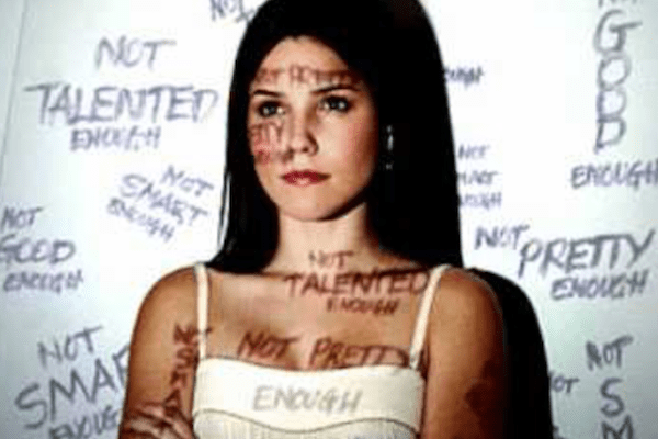 young woman with words of negative judgement around her and projected onto her face and body