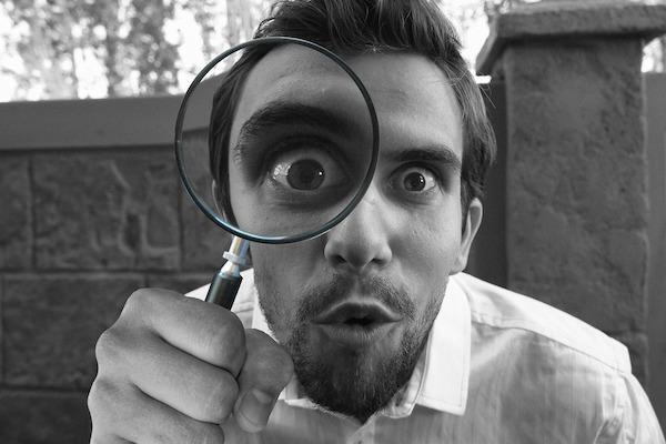 goofy picture of man looking through magnifying glass