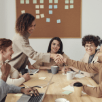 professionals around a conference table with man and woman shaking hands