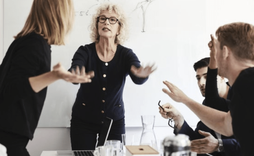 professional woman trying to calm a hostile group of coworkers arguing