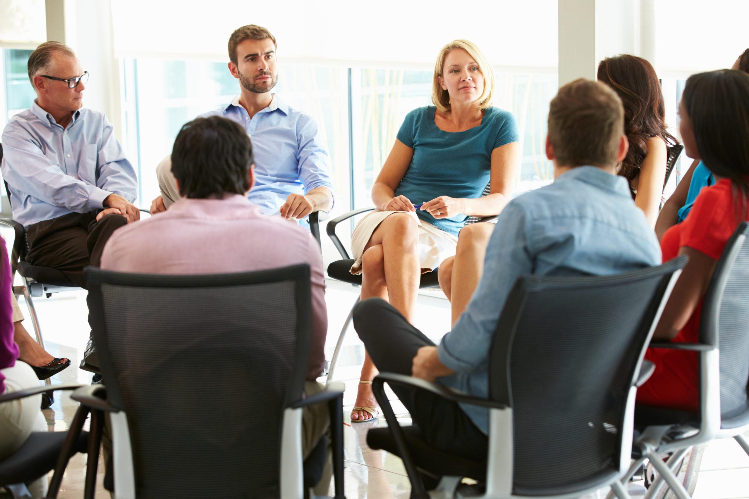 group of professionals in chairs in a circle talking