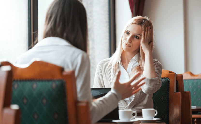 two woman at a cafe looking frustrated with each other