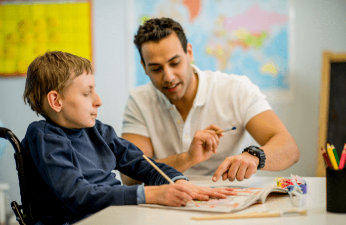Male teacher helps boy with disabilities