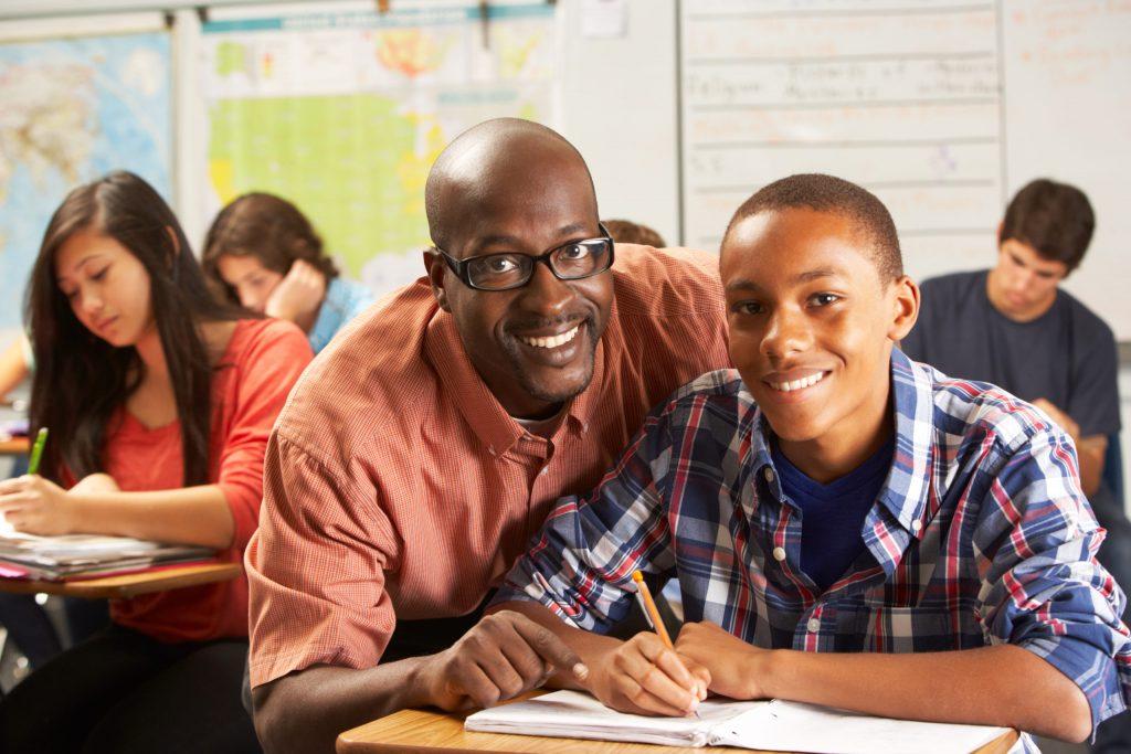 teacher helping teen student in classroom