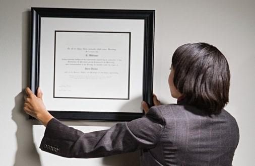 woman hanging a picture of her certificate