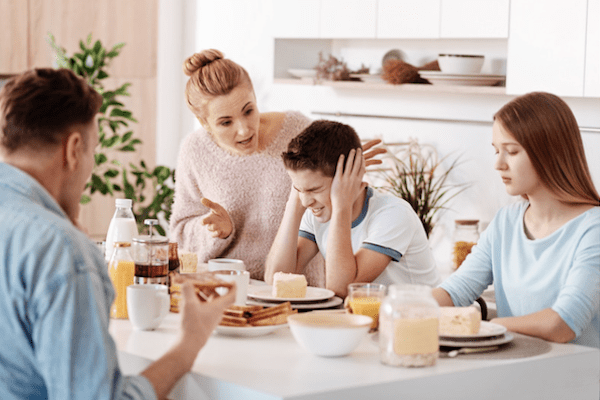 Mom yelling at son at dinner table with dad and sister