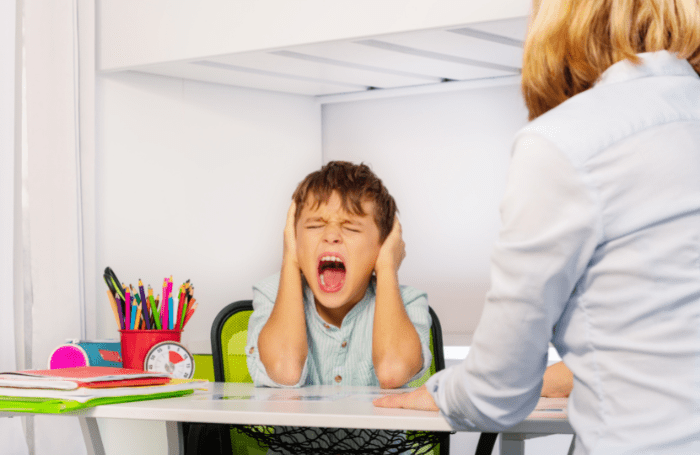 Child in highchair covering ears and screaming