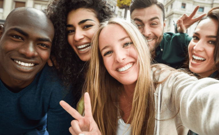 diverse group of young people smiling and giving peace sign