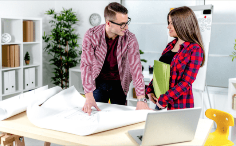 man and woman looking over blueprint and smiling