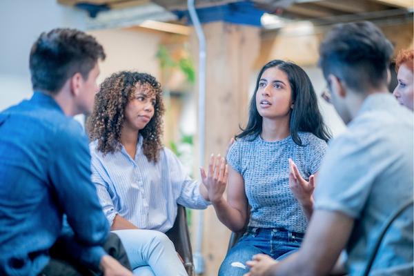 Group of diverse young adults in a circle sharing