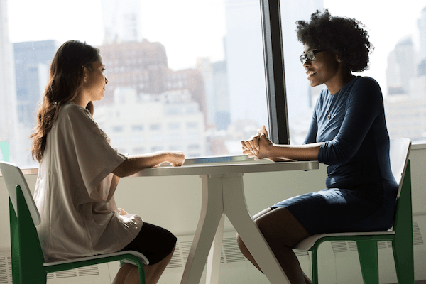 two women talk at table