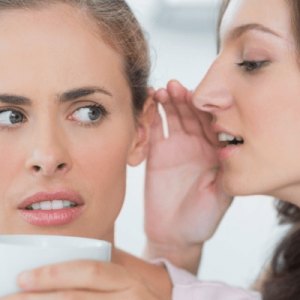 Women whispering a secret into another women's ear