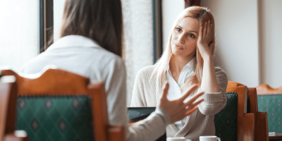 two woman at a cafe looking frustrated with each other