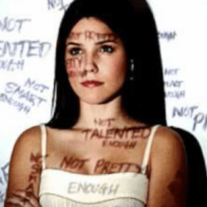 young woman with words of negative judgement around her and projected onto her face and body